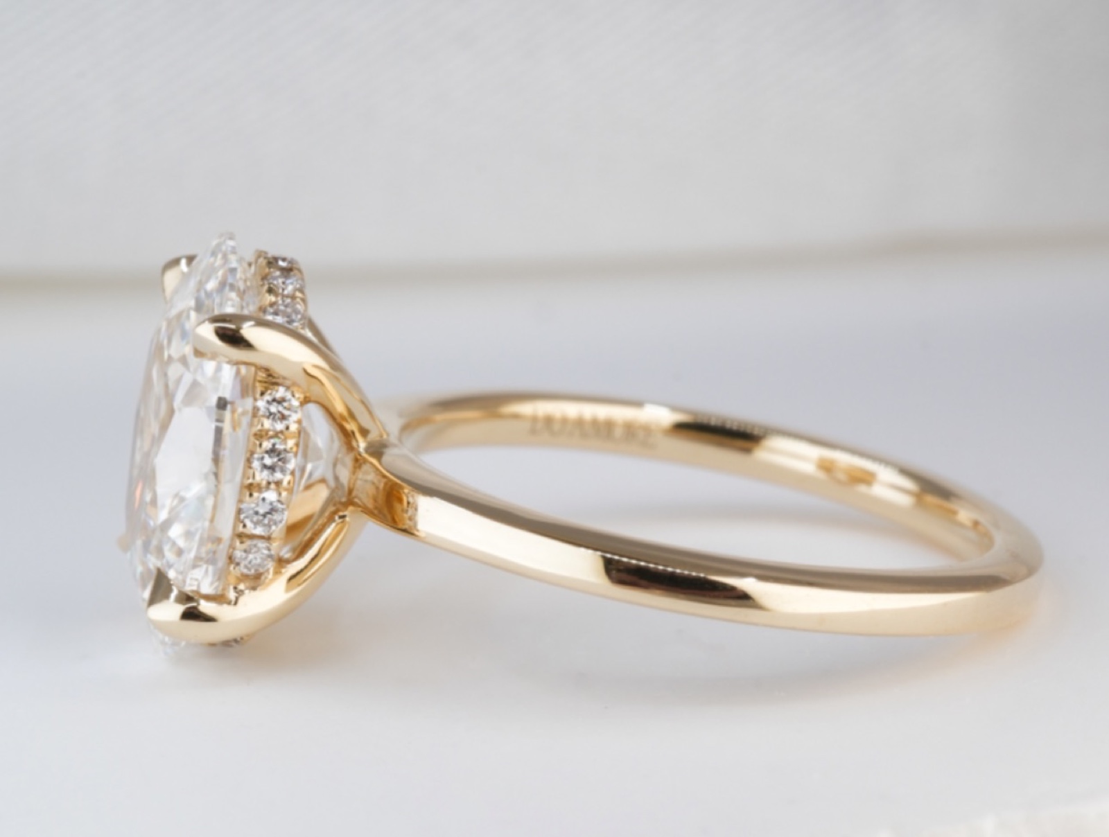 Side profile of a yellow gold engagement ring with a hidden diamond halo