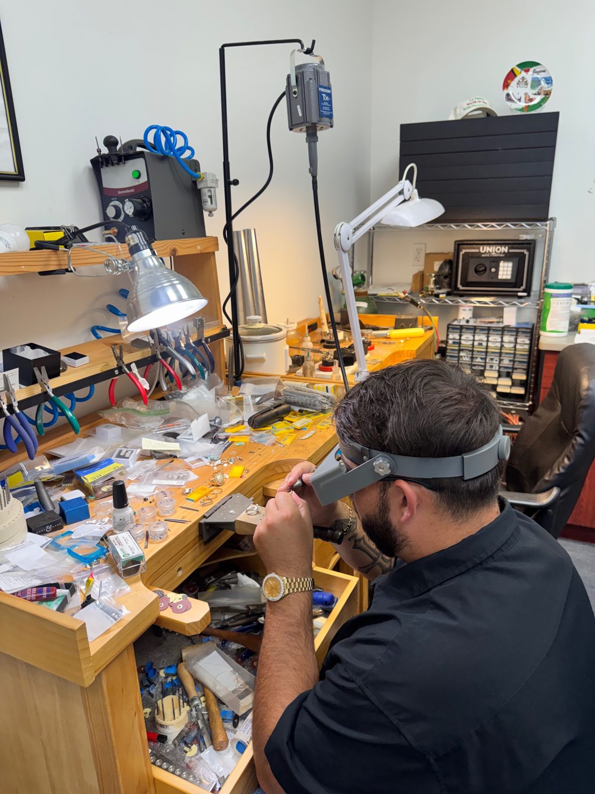 Kyle at his cluttered, well-used jeweler's workbench surrounded by tools