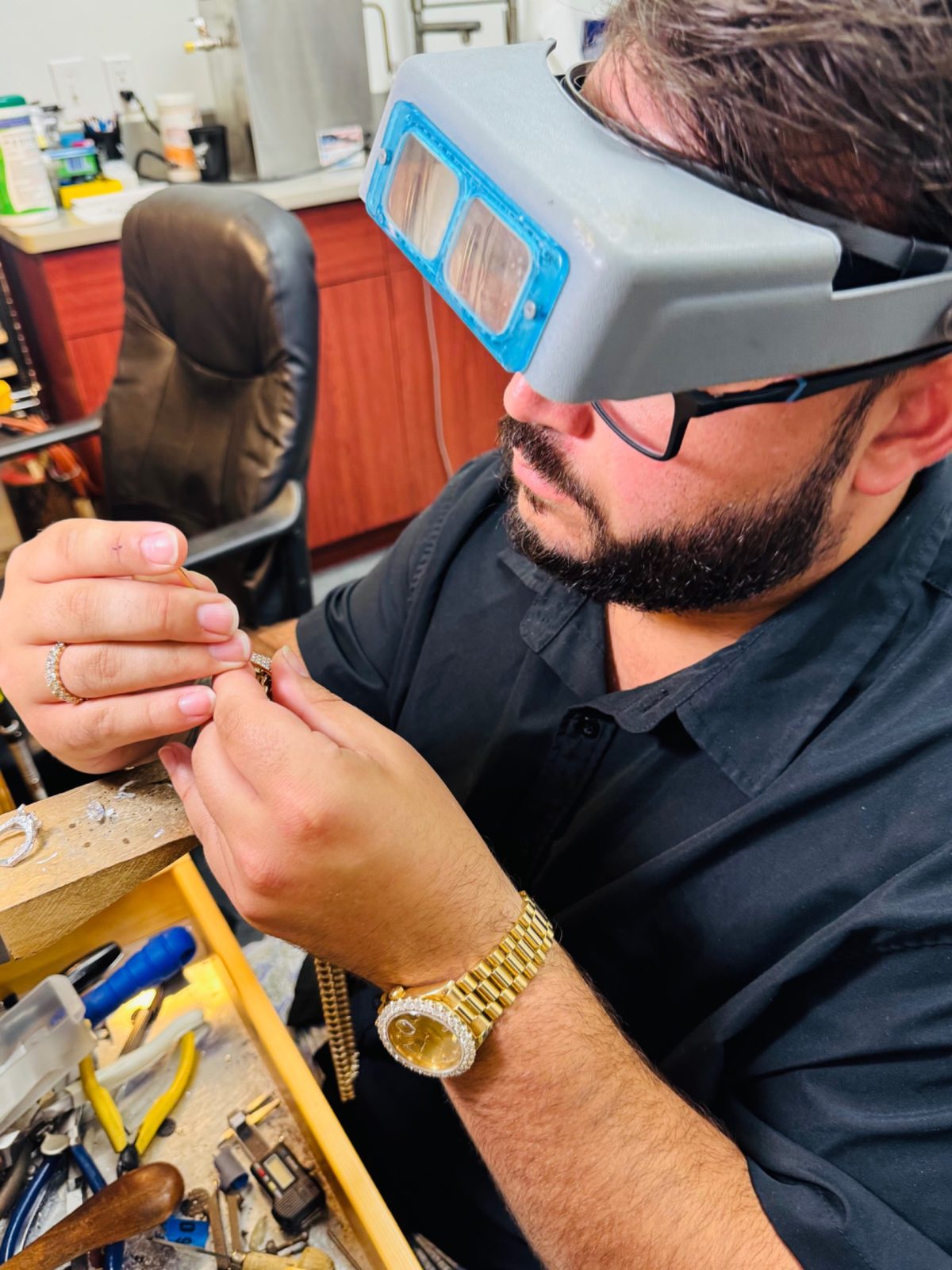 Kyle LaProva inspecting a piece with a magnifier at the jeweler's bench