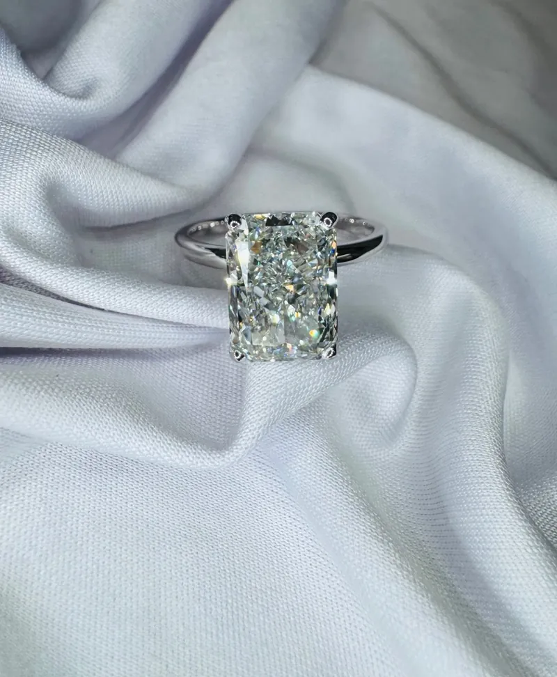 Radiant-cut diamond solitaire ring in white gold on soft fabric
