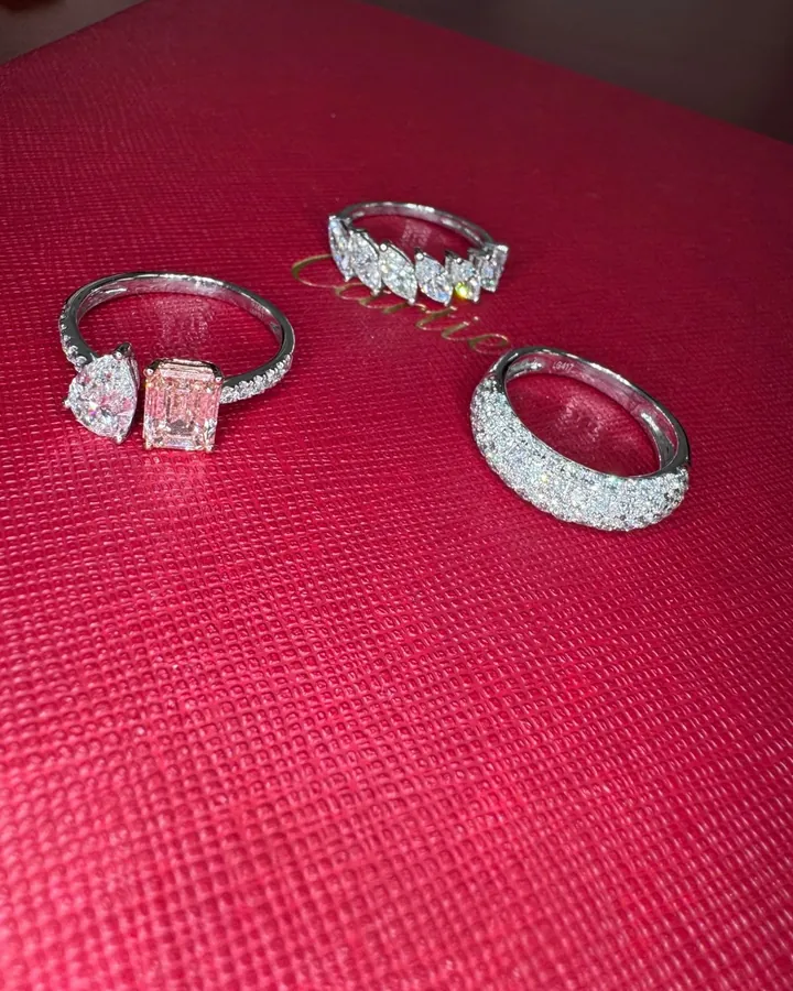 Three diamond statement rings displayed on a red presentation box, including a pink emerald-cut center stone