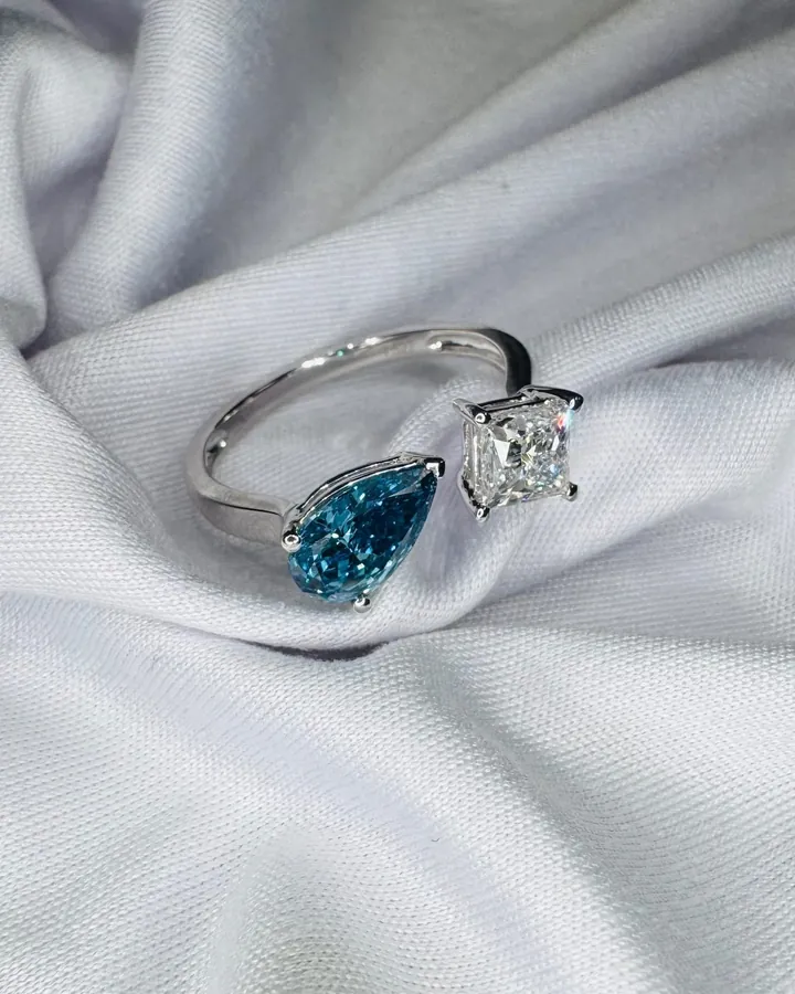 Toi et moi ring pairing a blue pear-shaped stone with a white princess-cut diamond