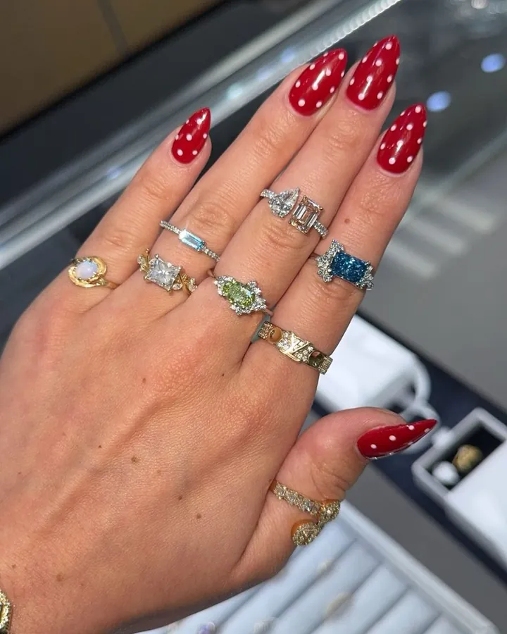 A hand styled with opal, blue, green, and white gemstone rings in mixed shapes