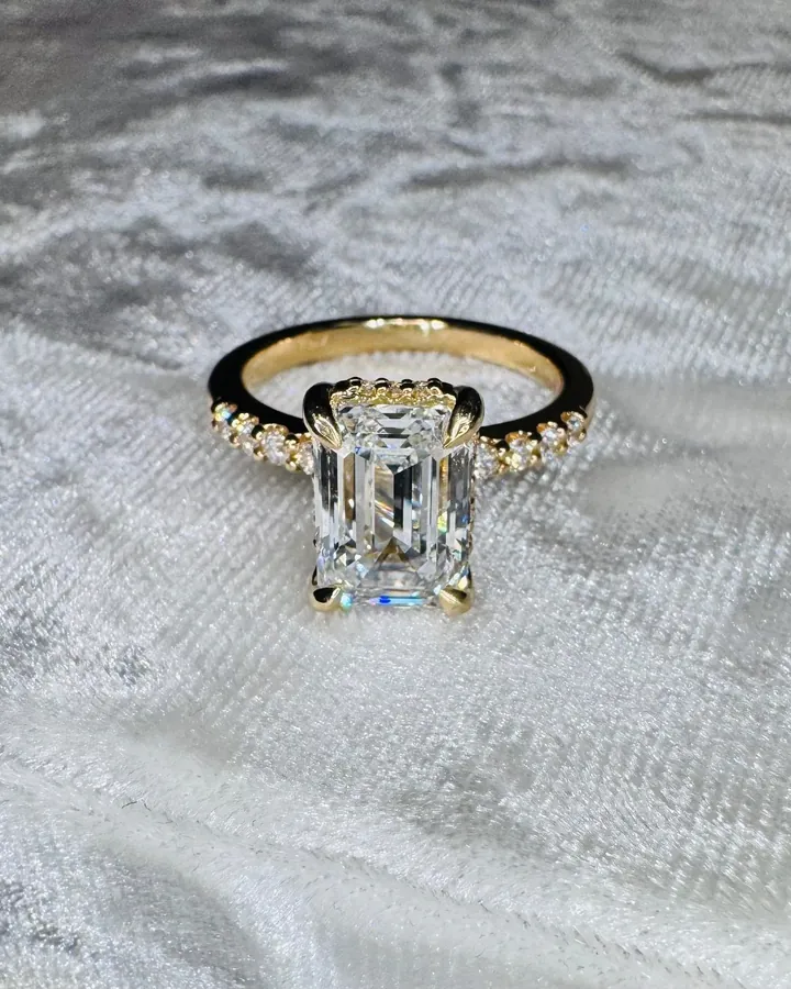 Emerald-cut diamond engagement ring in yellow gold with a diamond-accented band