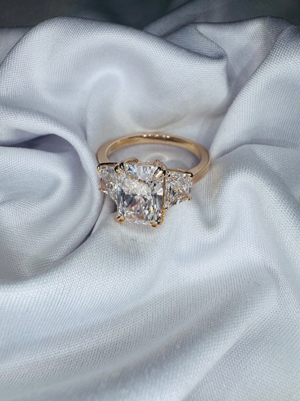Radiant-cut diamond flanked by trapezoid side stones in yellow gold