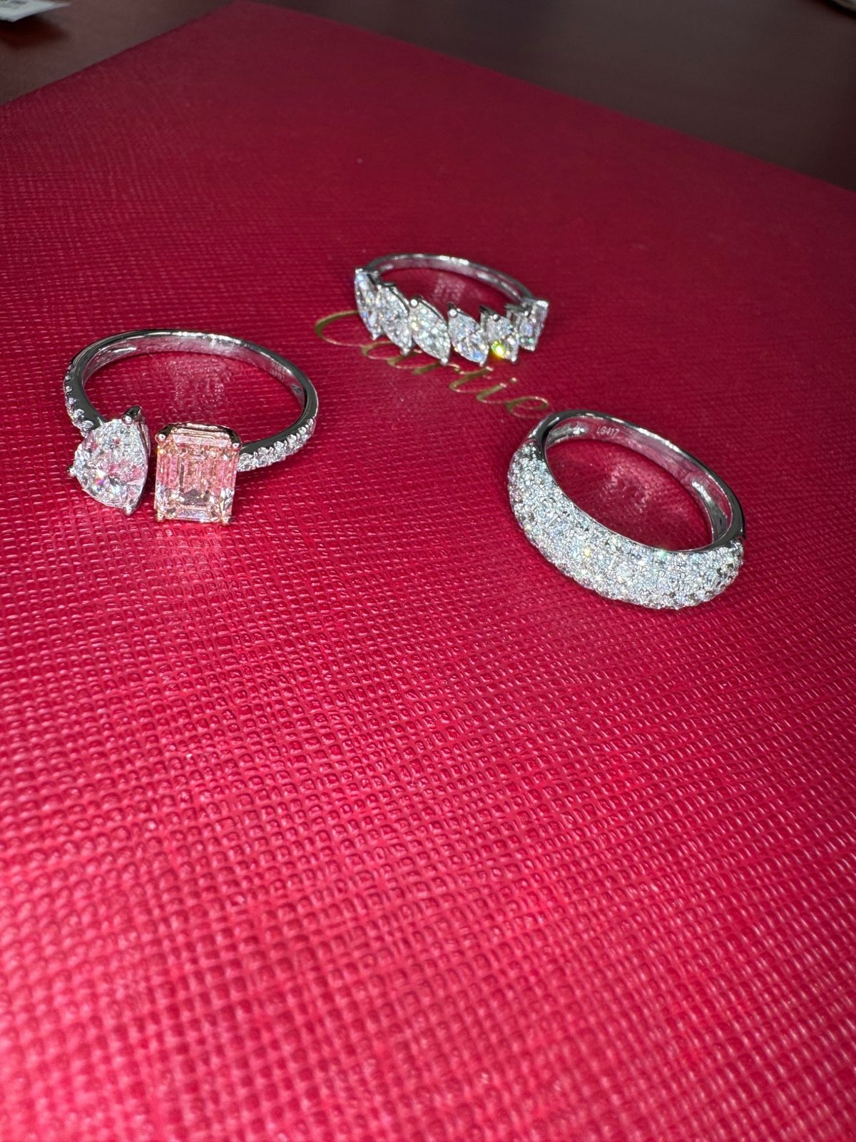Diamond rings including a pink center stone displayed on a jewelry box
