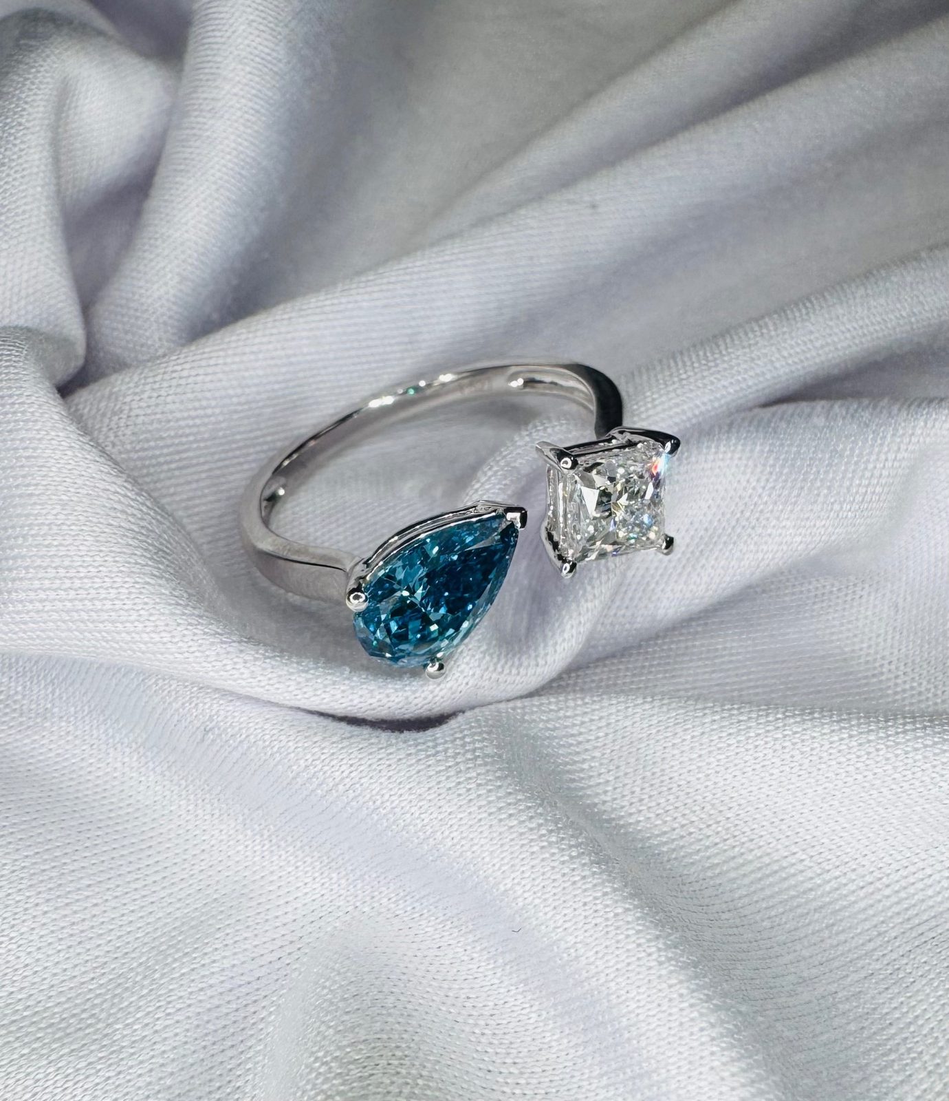 Open toi et moi ring with a blue pear and a white princess-cut diamond
