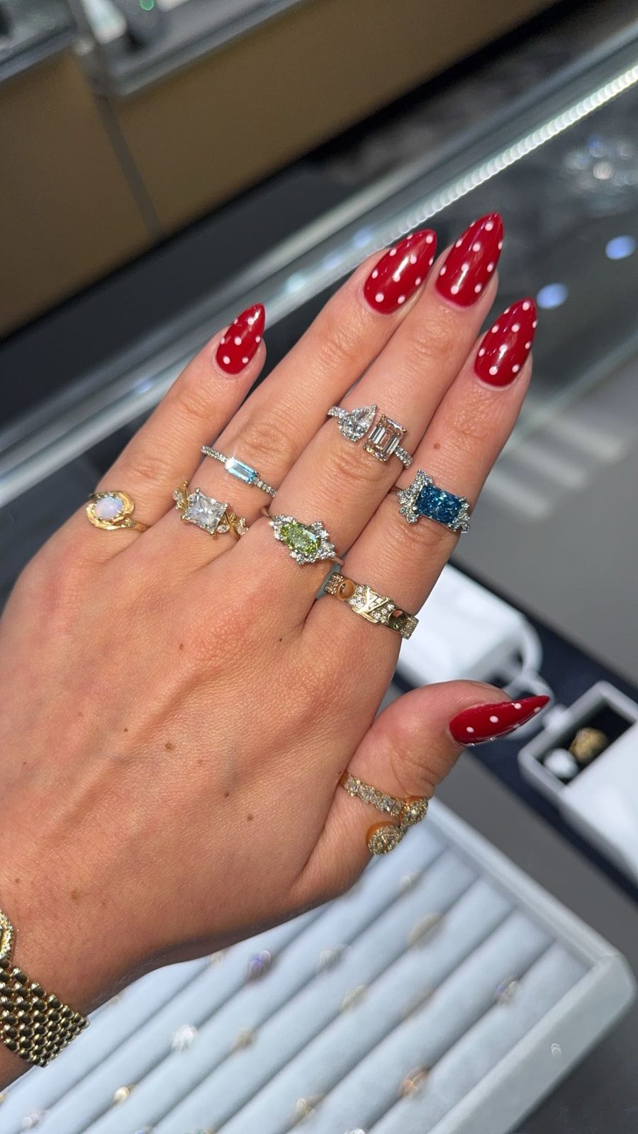 A hand wearing a collection of colored gemstone and diamond rings