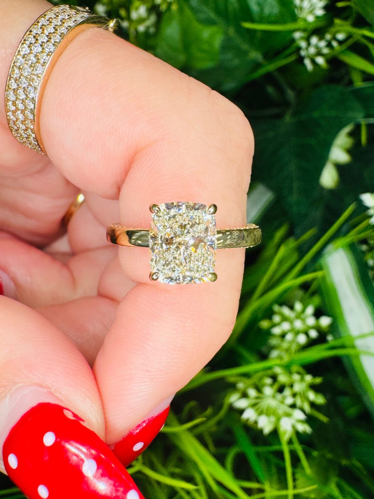 Cushion-cut diamond solitaire in yellow gold held in hand