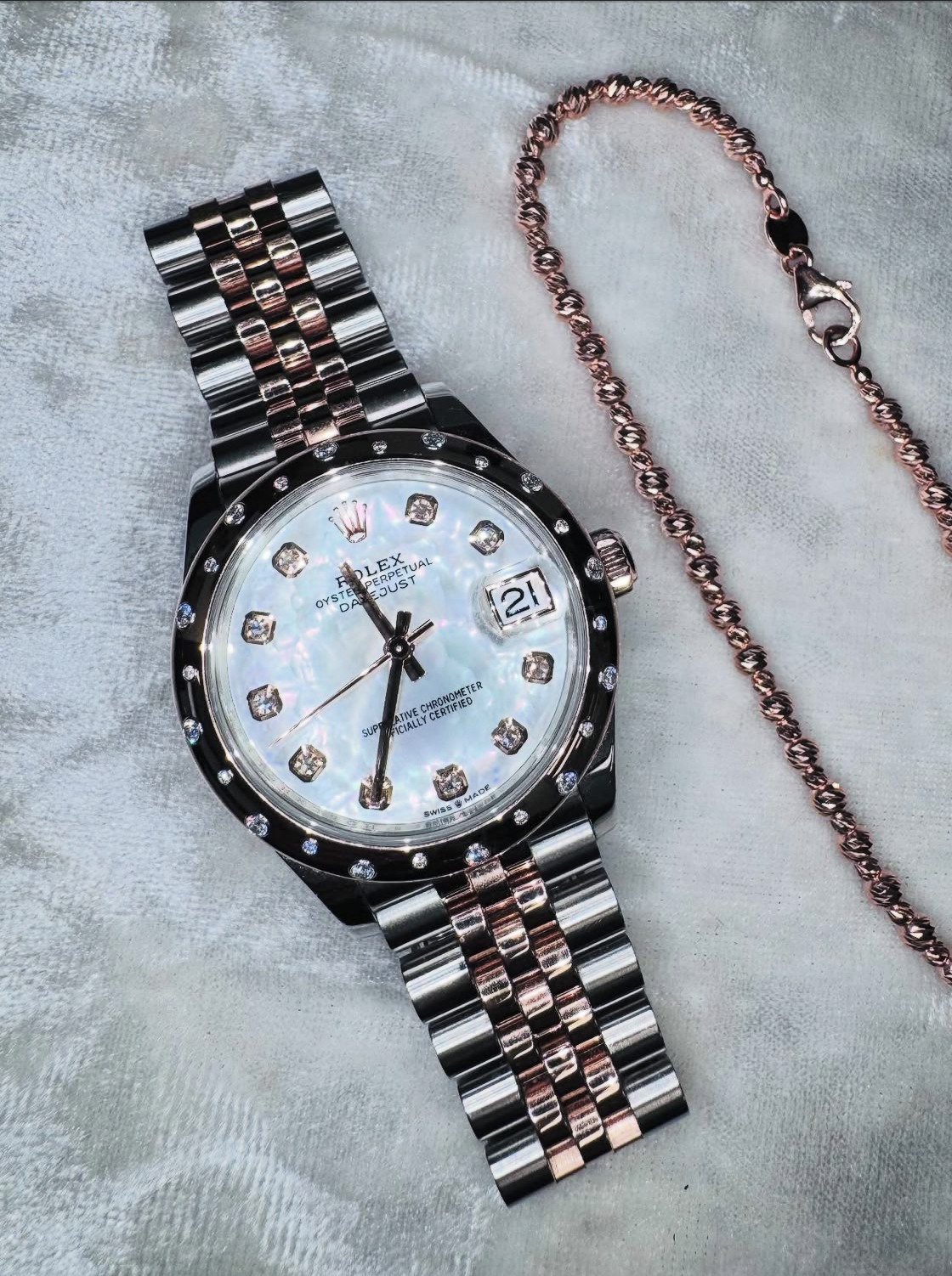 Diamond-dial two-tone luxury watch photographed on soft fabric
